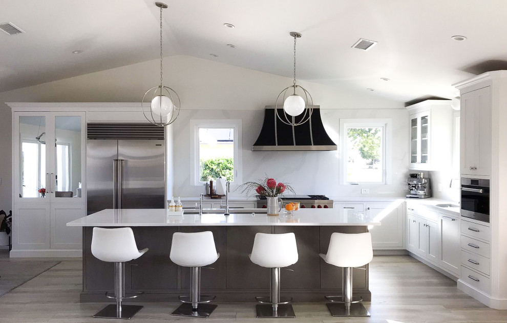 Inspiration for a transitional kitchen remodel with shaker cabinets, white cabinets, white backsplash, stainless steel appliances, an island and white countertops