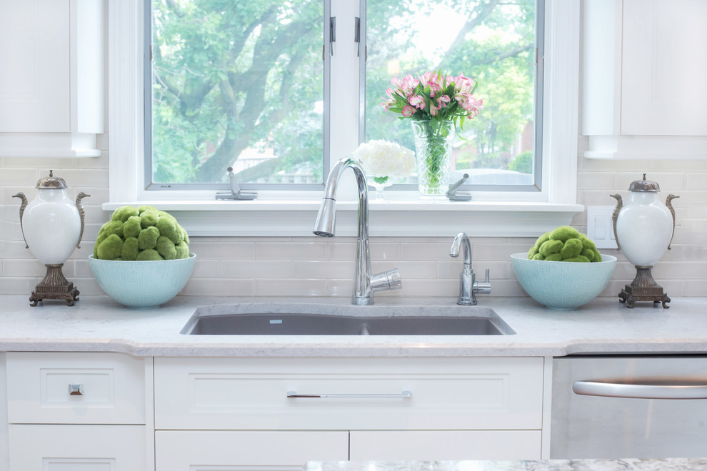 Inspiration for a mid-sized transitional u-shaped eat-in kitchen remodel in Toronto with shaker cabinets, white cabinets, white backsplash, an island, an undermount sink, quartz countertops and stainless steel appliances
