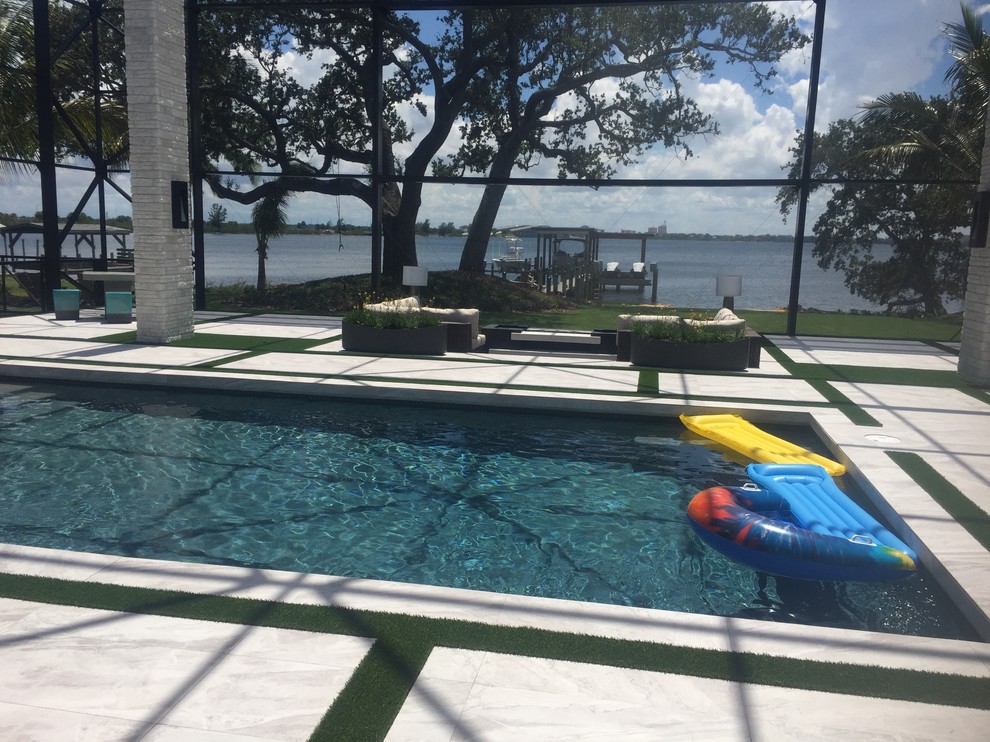 This is an example of an expansive modern backyard custom-shaped natural pool in Orlando with decking.