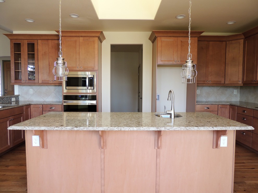 Large transitional u-shaped light wood floor eat-in kitchen photo in Seattle with recessed-panel cabinets, medium tone wood cabinets, multicolored backsplash, mosaic tile backsplash, stainless steel appliances, an island and quartz countertops