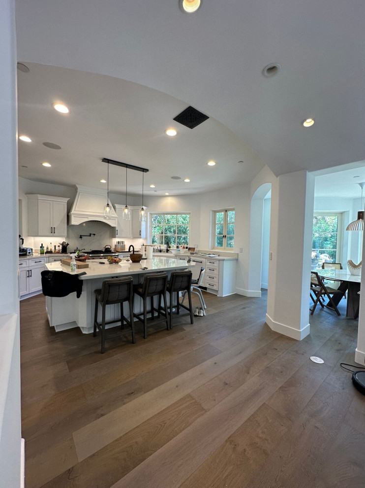 Modern kitchen in Los Angeles with an undermount sink, raised-panel cabinets, white cabinets, marble benchtops, multi-coloured splashback, marble splashback, white appliances, painted wood floors, with island, grey floor and multi-coloured benchtop.