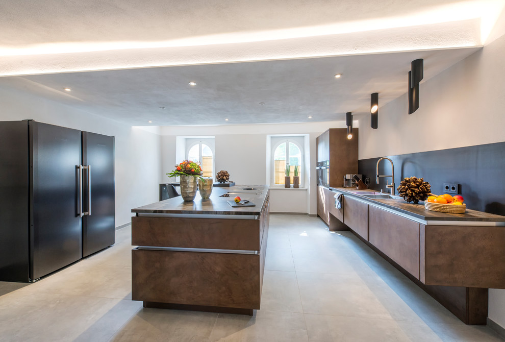 Inspiration for a mid-sized contemporary galley separate kitchen in Nuremberg with a double-bowl sink, flat-panel cabinets, brown cabinets, black appliances, cement tiles, multiple islands and grey floor.