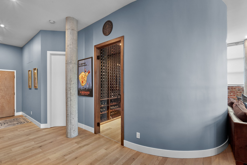 Design ideas for a mid-sized industrial wine cellar in Edmonton with light hardwood floors, display racks and beige floor.