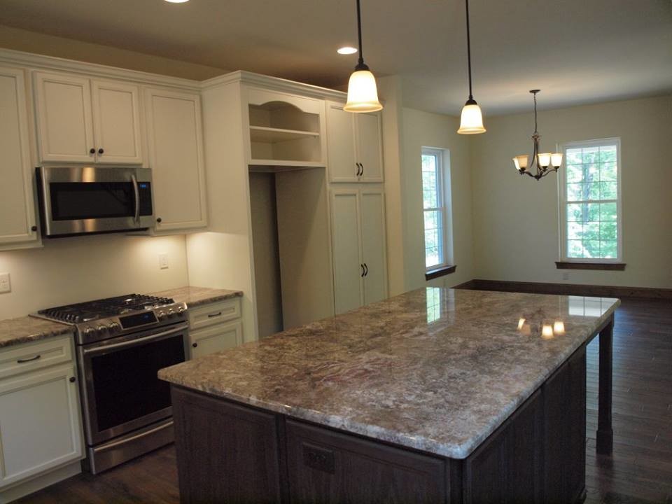 Mid-sized mountain style l-shaped dark wood floor and brown floor open concept kitchen photo with a single-bowl sink, recessed-panel cabinets, beige cabinets, granite countertops, stainless steel appliances, an island and brown countertops