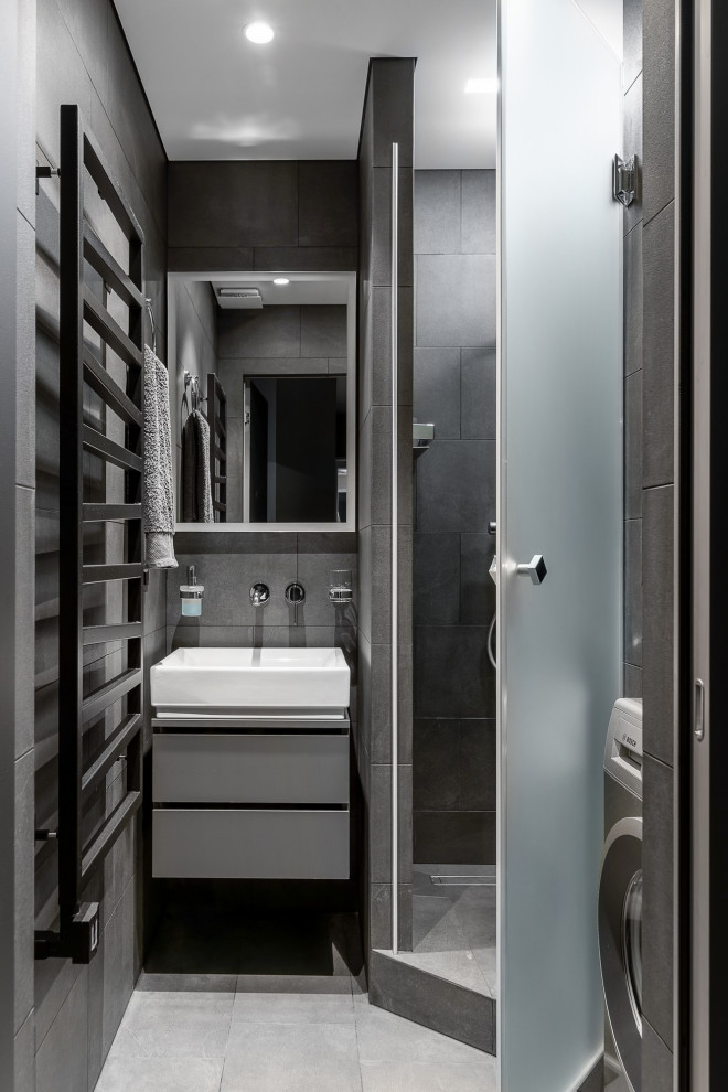 Пример оригинального дизайна: серо-белая ванная комната среднего размера со стиральной машиной в современном стиле с плоскими фасадами, серыми фасадами, угловой ванной, душевой комнатой, инсталляцией, серой плиткой, керамогранитной плиткой, серыми стенами, полом из керамогранита, душевой кабиной, накладной раковиной, столешницей из искусственного кварца, серым полом, душем с распашными дверями, белой столешницей, тумбой под одну раковину и подвесной тумбой