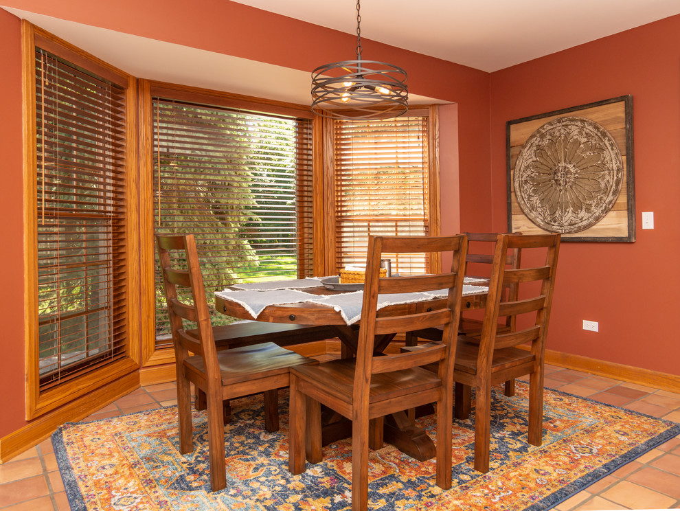 Photo of a small country separate dining room in Chicago with red walls, terra-cotta floors, no fireplace and red floor.