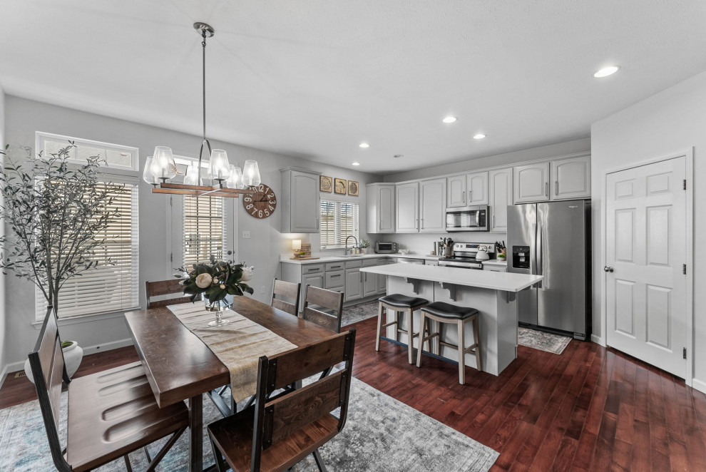 Example of a transitional dark wood floor eat-in kitchen design with a double-bowl sink, gray cabinets, quartz countertops, stainless steel appliances, an island and white countertops