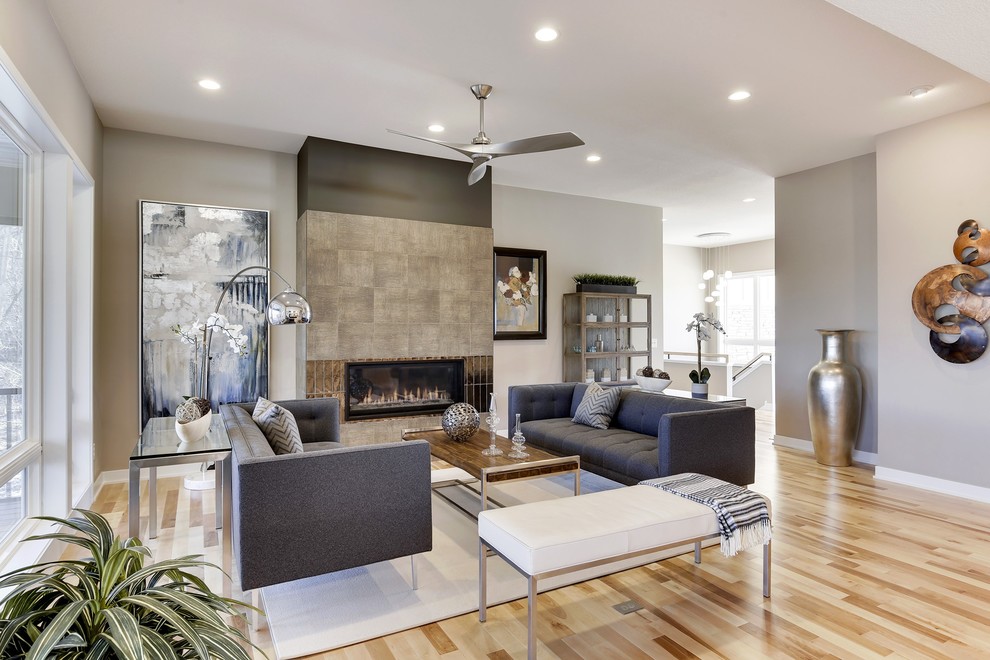 Photo of a mid-sized modern open concept living room in Minneapolis with grey walls, light hardwood floors, a ribbon fireplace, a tile fireplace surround and a wall-mounted tv.