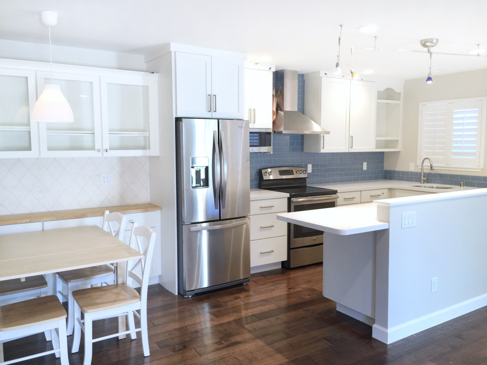 Eat-in kitchen - small transitional u-shaped medium tone wood floor eat-in kitchen idea with an undermount sink, shaker cabinets, white cabinets, quartzite countertops, blue backsplash, glass tile backsplash, stainless steel appliances and white countertops