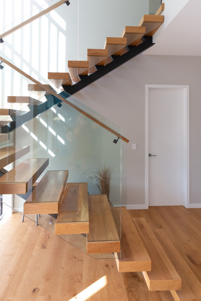 Mid-sized modern wood floating staircase in Auckland with open risers and mixed railing.