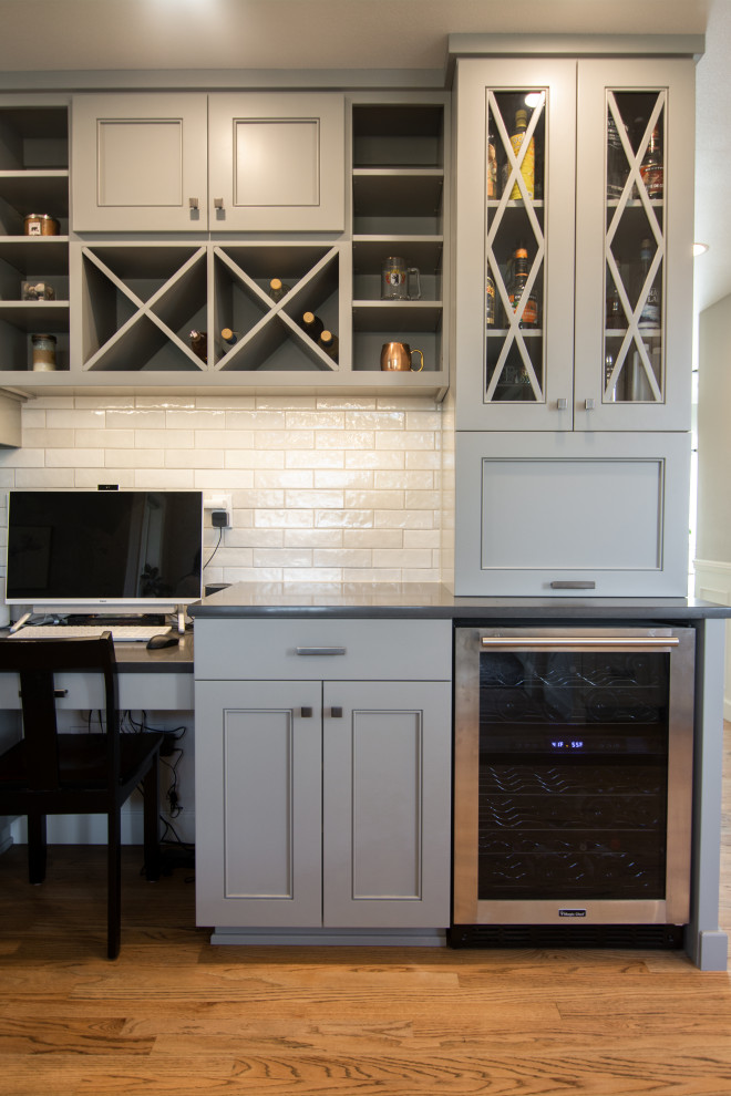 Inspiration for a mid-sized transitional l-shaped medium tone wood floor and brown floor kitchen remodel with an undermount sink, recessed-panel cabinets, gray cabinets, quartz countertops, white backsplash, ceramic backsplash, stainless steel appliances, a peninsula and white countertops