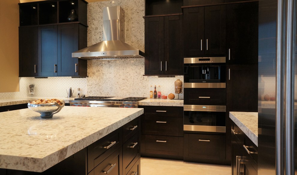 Inspiration for a transitional l-shaped porcelain tile and beige floor kitchen remodel in Phoenix with an undermount sink, recessed-panel cabinets, dark wood cabinets, quartz countertops, white backsplash, ceramic backsplash, stainless steel appliances and an island
