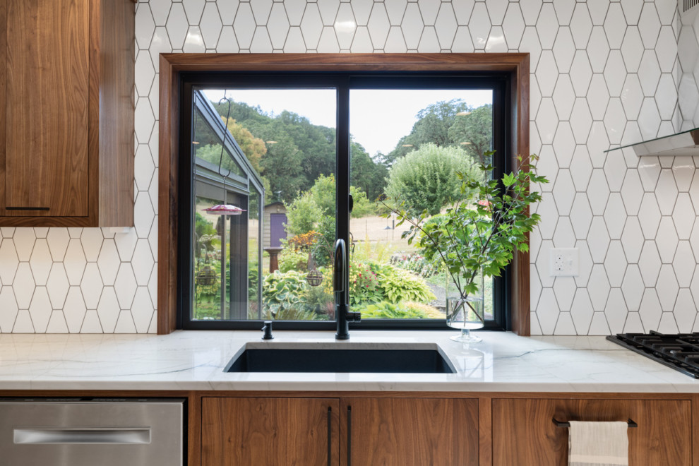 Photo of a mid-sized midcentury u-shaped eat-in kitchen in Other with a double-bowl sink, flat-panel cabinets, dark wood cabinets, quartz benchtops, white splashback, ceramic splashback, stainless steel appliances, light hardwood floors, with island, multi-coloured floor and white benchtop.