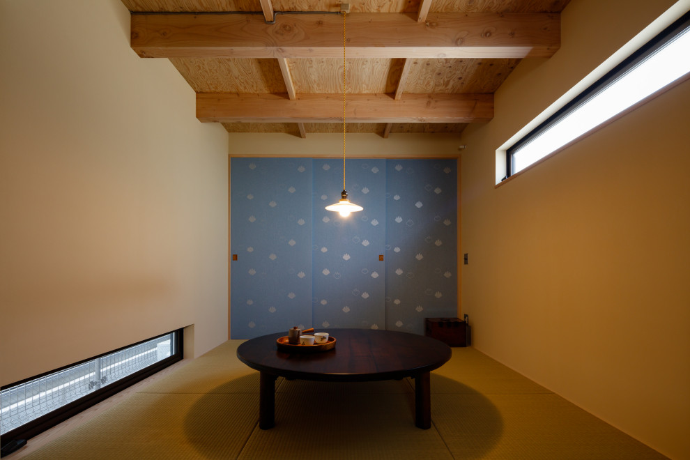 Cette image montre une petite salle à manger ouverte sur le salon en bois avec un mur beige, un sol de tatami et poutres apparentes.