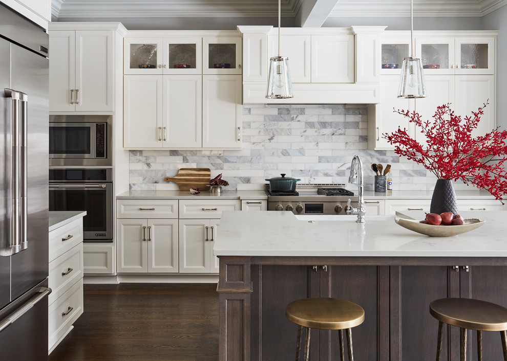 Inspiration for a large transitional l-shaped kitchen in Chicago with a farmhouse sink, shaker cabinets, white cabinets, quartz benchtops, marble splashback, stainless steel appliances, with island, brown floor, multi-coloured splashback, dark hardwood floors and grey benchtop.