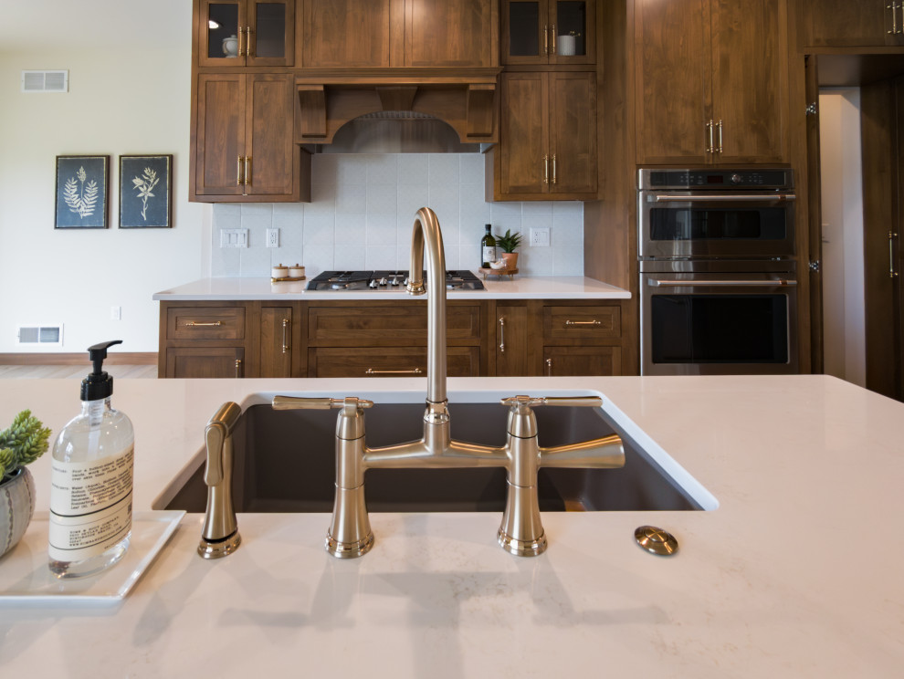 Open concept kitchen - transitional galley open concept kitchen idea with shaker cabinets, medium tone wood cabinets, quartz countertops, white backsplash, porcelain backsplash, stainless steel appliances, an island and white countertops