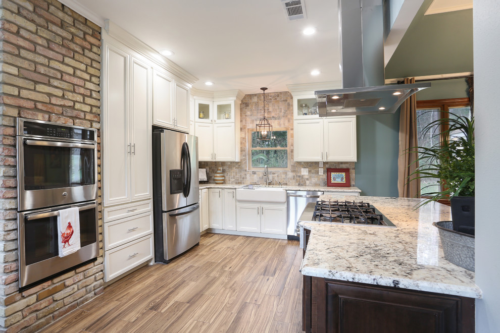 Inspiration for a large transitional l-shaped eat-in kitchen in New Orleans with a farmhouse sink, recessed-panel cabinets, white cabinets, granite benchtops, beige splashback, stone tile splashback, stainless steel appliances, porcelain floors, with island, beige floor and grey benchtop.