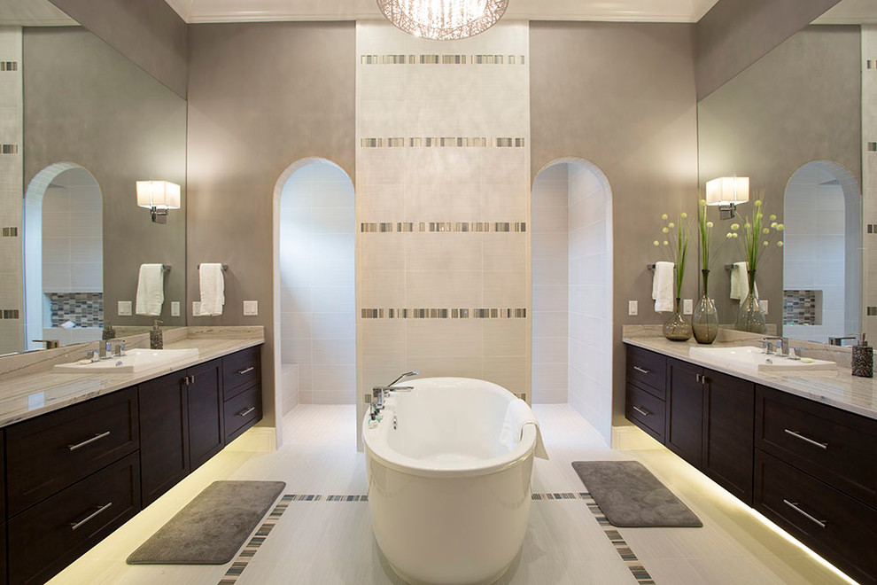 Design ideas for a transitional master bathroom in Orlando with porcelain floors, a drop-in sink, engineered quartz benchtops, shaker cabinets, dark wood cabinets, a freestanding tub, porcelain tile, grey walls and beige tile.