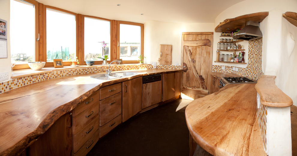 Photo of a country galley separate kitchen in Other with a drop-in sink, flat-panel cabinets, medium wood cabinets, wood benchtops, multi-coloured splashback, mosaic tile splashback and panelled appliances.