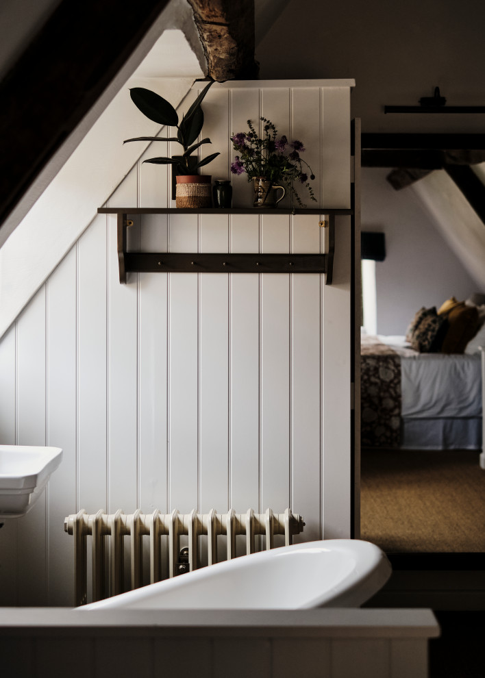 Design ideas for a mid-sized country bathroom in Oxfordshire with a claw-foot tub, a wall-mount sink, an enclosed toilet, exposed beam and planked wall panelling.