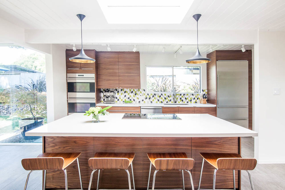 Photo of a mid-sized midcentury galley open plan kitchen in San Francisco with an undermount sink, flat-panel cabinets, medium wood cabinets, quartz benchtops, multi-coloured splashback, ceramic splashback, stainless steel appliances, ceramic floors, with island and grey floor.