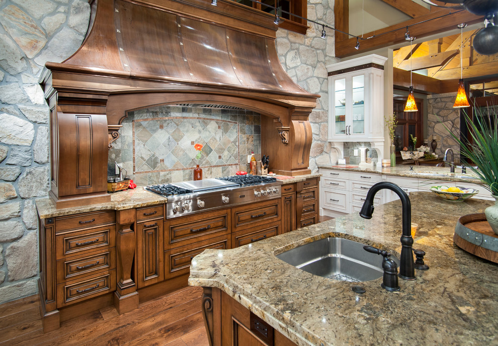 This is an example of a large country u-shaped kitchen in Vancouver with raised-panel cabinets, dark wood cabinets, panelled appliances, medium hardwood floors, with island, multi-coloured splashback and stone tile splashback.