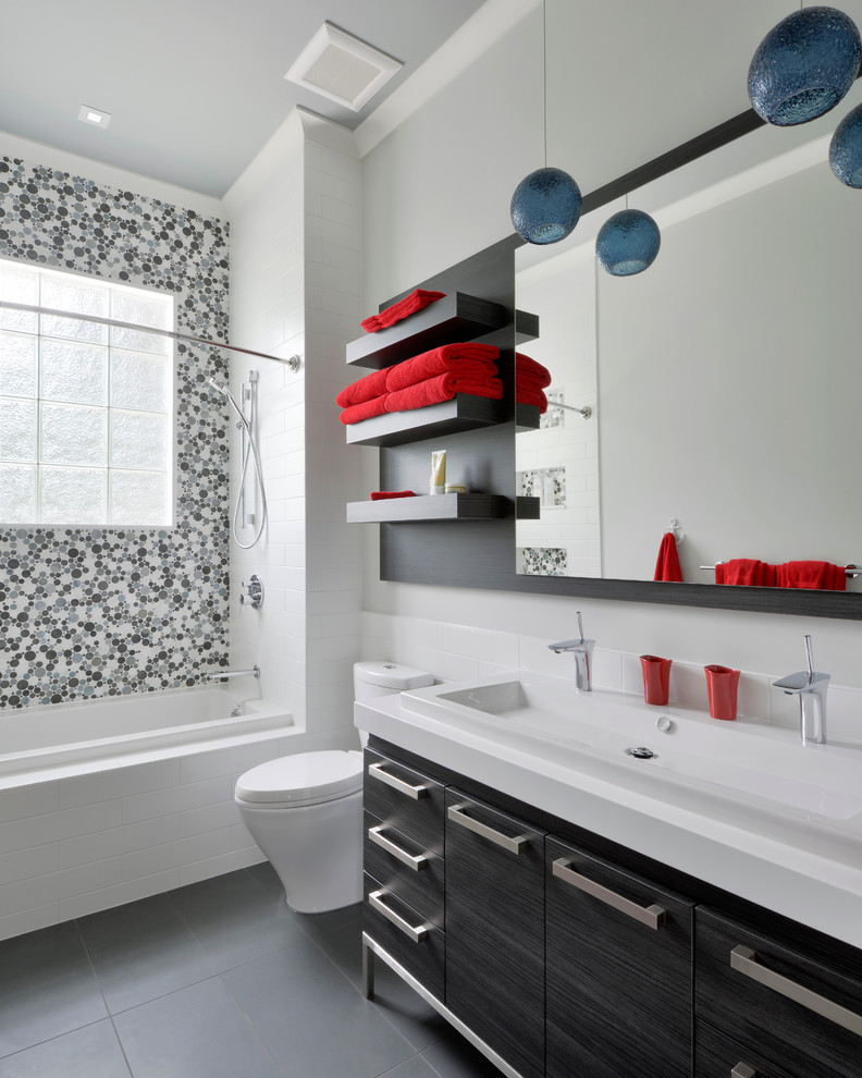This is an example of a contemporary bathroom in Toronto with a trough sink, flat-panel cabinets, a drop-in tub, a shower/bathtub combo, gray tile and mosaic tile.