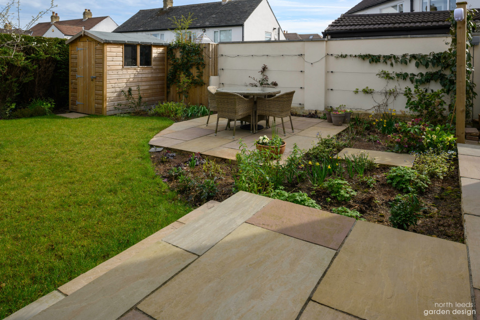 Photo of a small backyard partial sun garden with with flowerbed and natural stone pavers.
