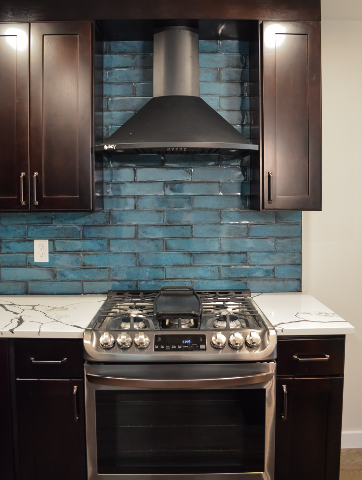 Mid-sized eclectic l-shaped vinyl floor and brown floor eat-in kitchen photo in Other with a drop-in sink, shaker cabinets, dark wood cabinets, quartz countertops, blue backsplash, subway tile backsplash, stainless steel appliances, an island and white countertops