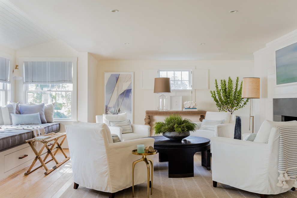 This is an example of a mid-sized beach style formal open concept living room in Boston with white walls, light hardwood floors, a standard fireplace, beige floor, a concrete fireplace surround and no tv.