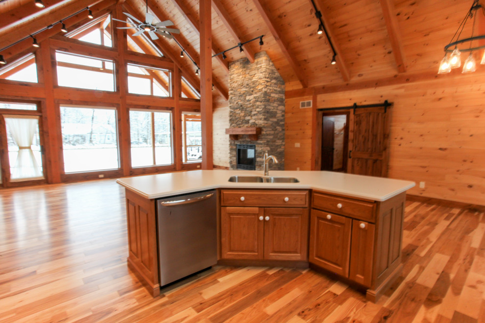 Mountain style u-shaped light wood floor, yellow floor and wood ceiling eat-in kitchen photo with a double-bowl sink, raised-panel cabinets, medium tone wood cabinets, wood backsplash, stainless steel appliances, an island and white countertops