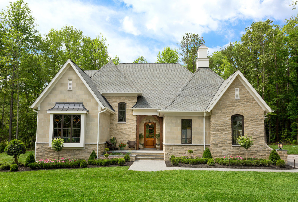 This is an example of a mid-sized transitional two-storey beige exterior in Richmond with stone veneer and a gambrel roof.