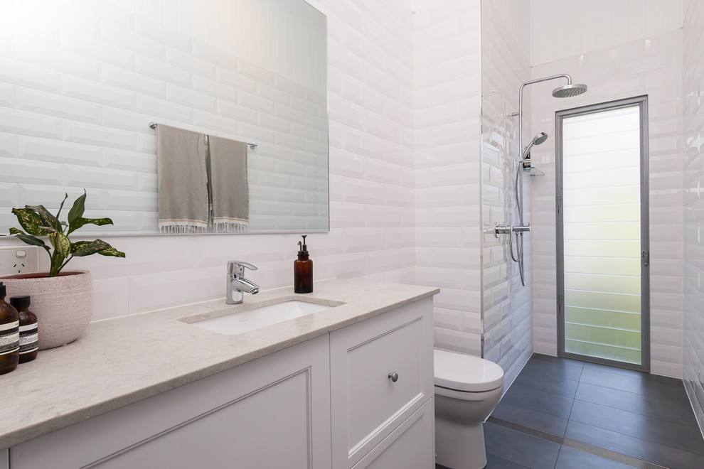 Photo of a mid-sized transitional master bathroom in Brisbane with shaker cabinets, white cabinets, an open shower, a one-piece toilet, white tile, subway tile, white walls, porcelain floors, an undermount sink, engineered quartz benchtops and grey floor.