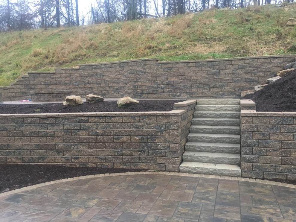 Photo of a mid-sized transitional backyard stone landscaping.