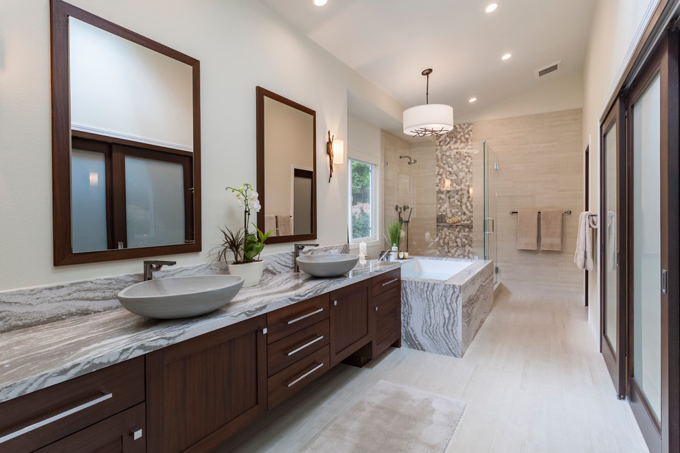 This is an example of a mid-sized transitional master bathroom in Los Angeles with louvered cabinets, dark wood cabinets, an undermount tub, a corner shower, pebble tile, beige walls, porcelain floors, a vessel sink, engineered quartz benchtops, beige floor, a hinged shower door and multi-coloured benchtops.