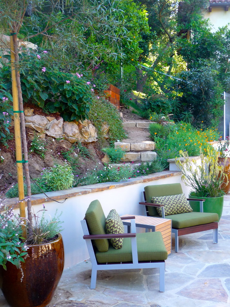This is an example of a large midcentury backyard patio in Los Angeles with natural stone pavers.