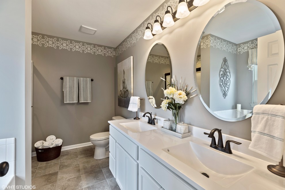 Design ideas for a large traditional master bathroom in Chicago with recessed-panel cabinets, white cabinets, a corner tub, an alcove shower, a one-piece toilet, white tile, ceramic tile, white walls, ceramic floors, a drop-in sink, engineered quartz benchtops, beige floor, a sliding shower screen and white benchtops.