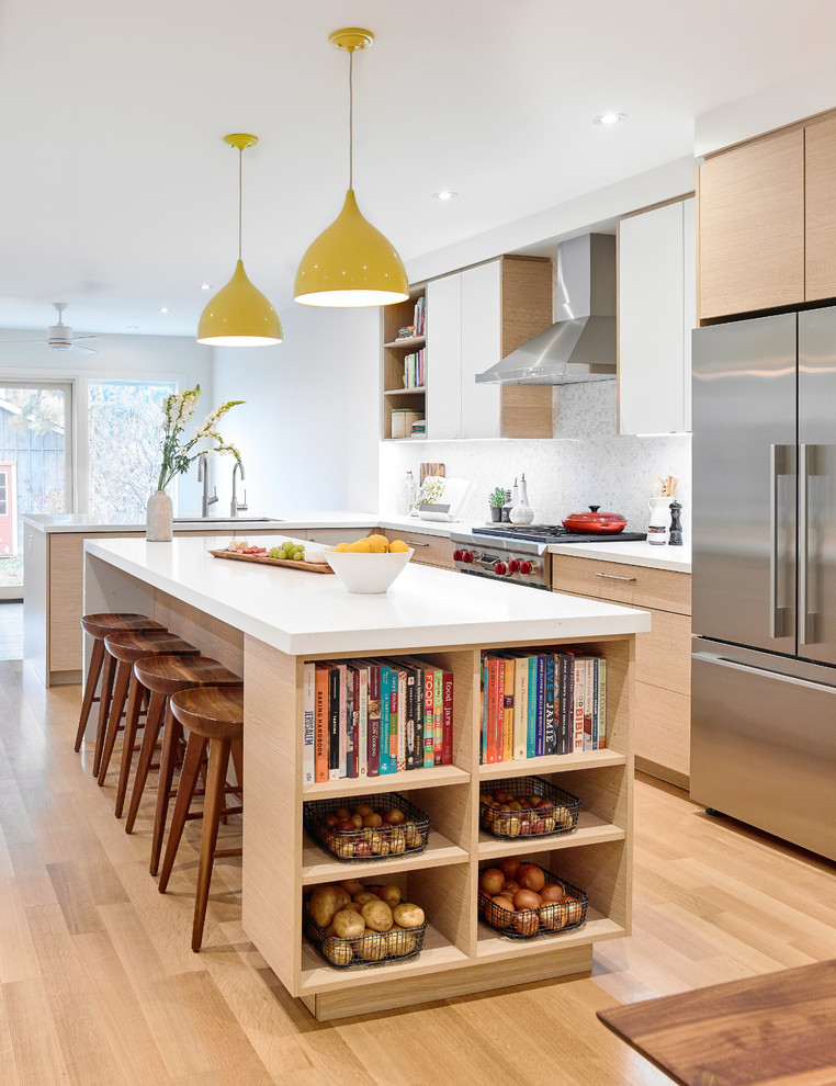 Photo of a contemporary l-shaped kitchen in Toronto with an undermount sink, flat-panel cabinets, light wood cabinets, grey splashback, stainless steel appliances, light hardwood floors, with island, beige floor and white benchtop.