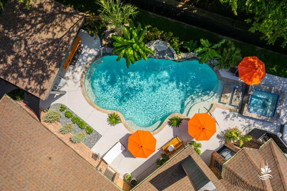 Ejemplo de piscina natural asiática extra grande a medida en patio trasero con privacidad y adoquines de piedra natural