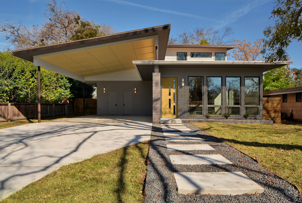 Photo of a mid-sized midcentury two-storey grey house exterior in Austin with wood siding and a gable roof.