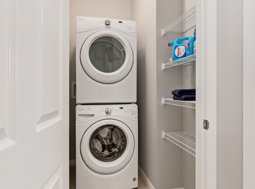 Inspiration for a small contemporary laundry cupboard in Calgary with grey walls, a stacked washer and dryer and linoleum floors.