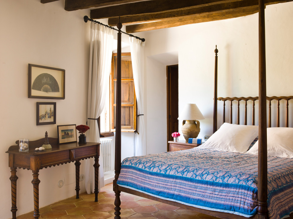 Country guest bedroom in Palma de Mallorca with white walls and terra-cotta floors.