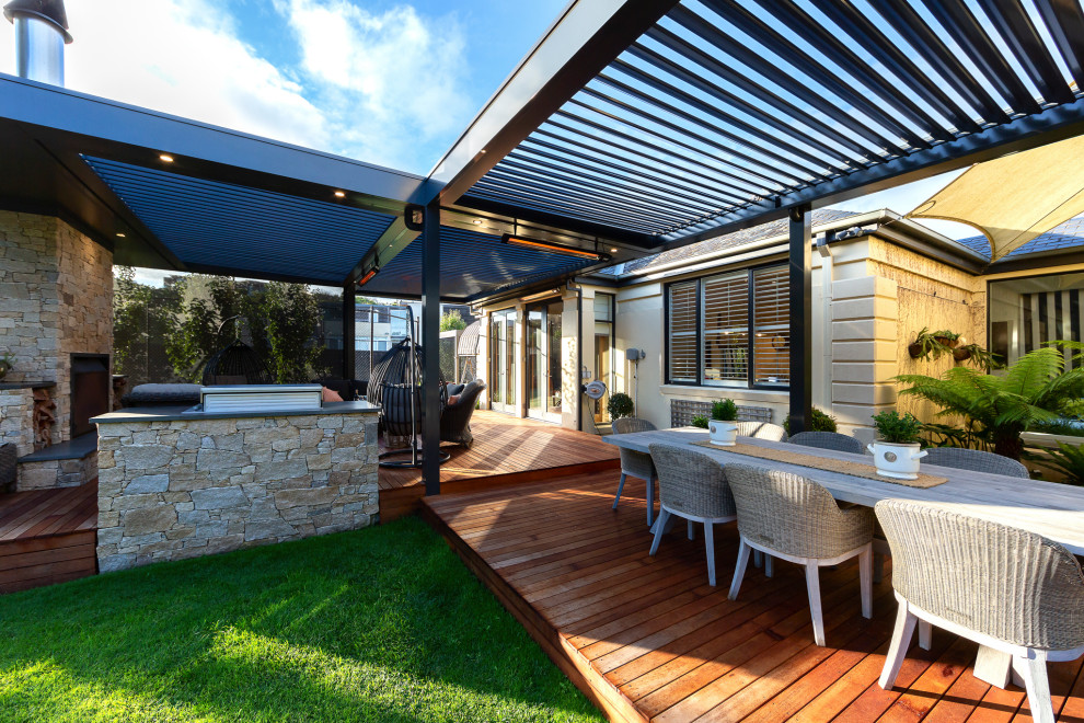 Large contemporary backyard verandah in Melbourne with with fireplace, decking and a pergola.