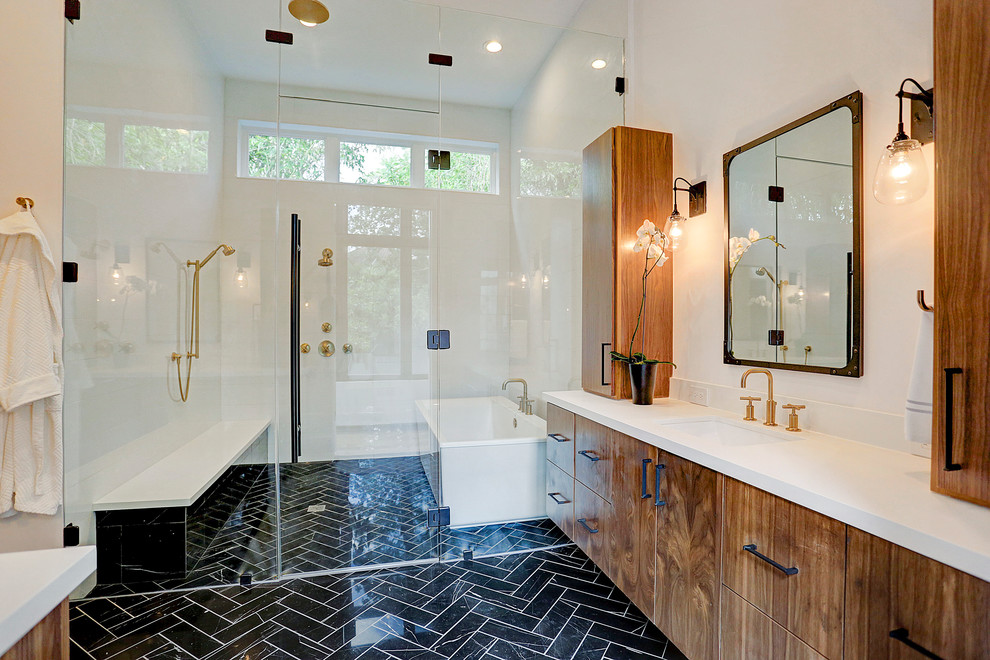 Design ideas for a large contemporary master wet room bathroom with flat-panel cabinets, medium wood cabinets, a freestanding tub, a two-piece toilet, white walls, marble floors, an undermount sink, quartzite benchtops, black floor, a hinged shower door and white benchtops.