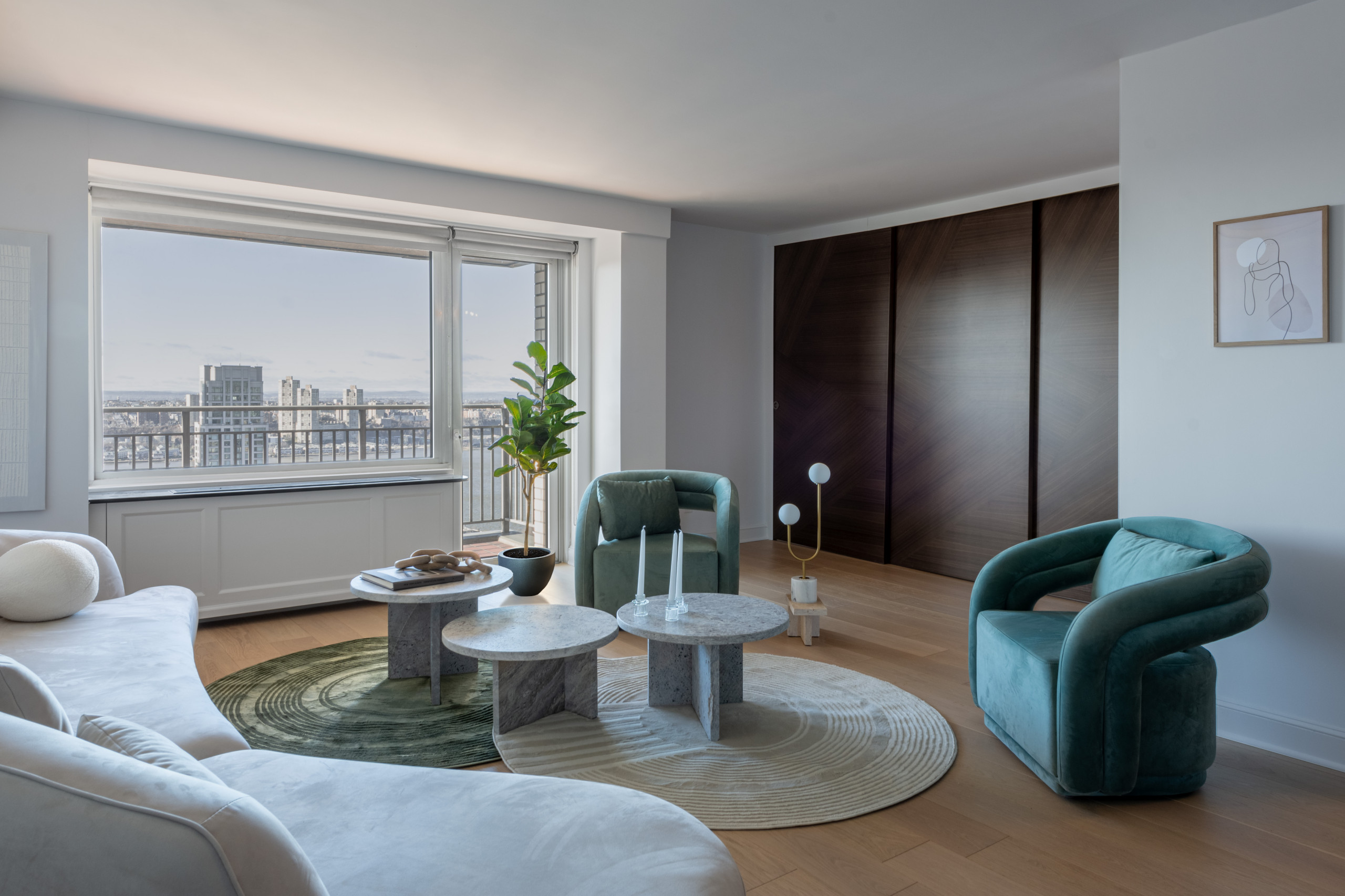 This living space is a perfect blend of modern sophistication and inviting comfort. A curvaceous cream sofa anchors the room, complemented by bold green velvet armchairs for a touch of color. Layered