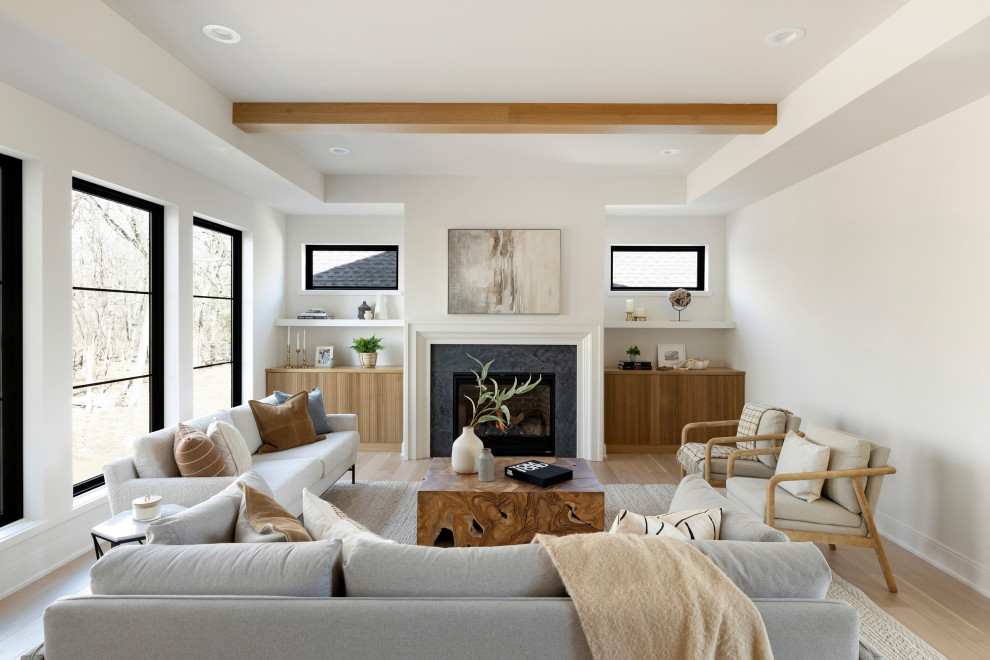 На фото: открытая гостиная комната в стиле неоклассика (современная классика) с белыми стенами, светлым паркетным полом, стандартным камином и сводчатым потолком с