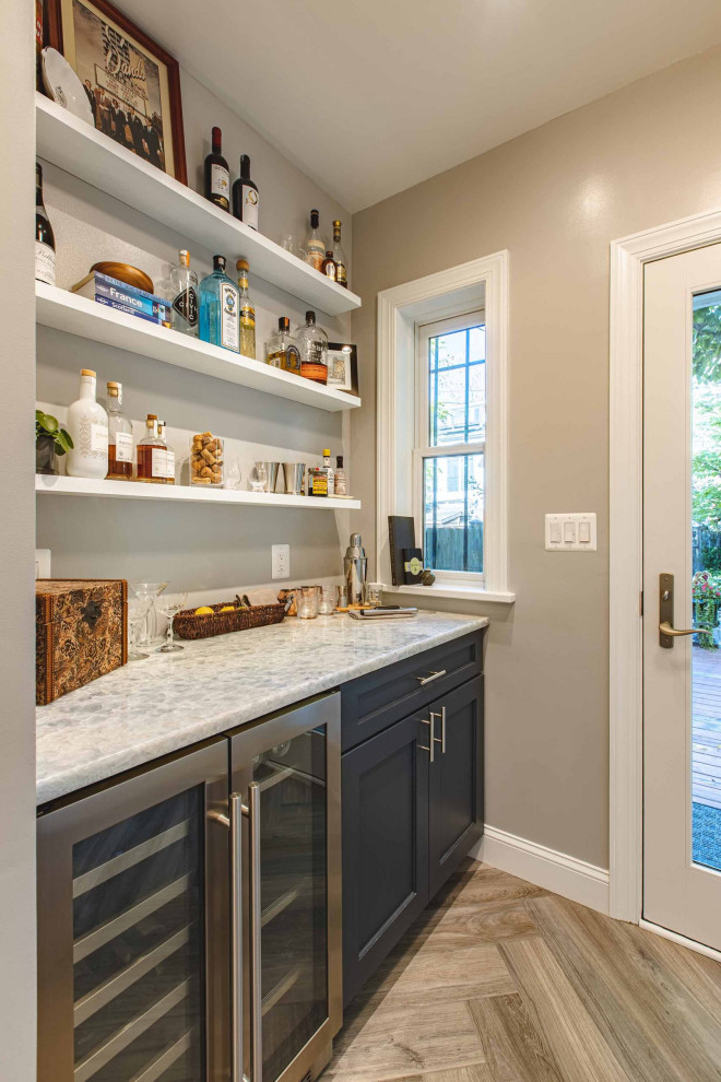 Bild på ett stort amerikanskt grå grått kök, med en undermonterad diskho, skåp i shakerstil, blå skåp, bänkskiva i kvarts, vitt stänkskydd, stänkskydd i porslinskakel, färgglada vitvaror, ljust trägolv och brunt golv