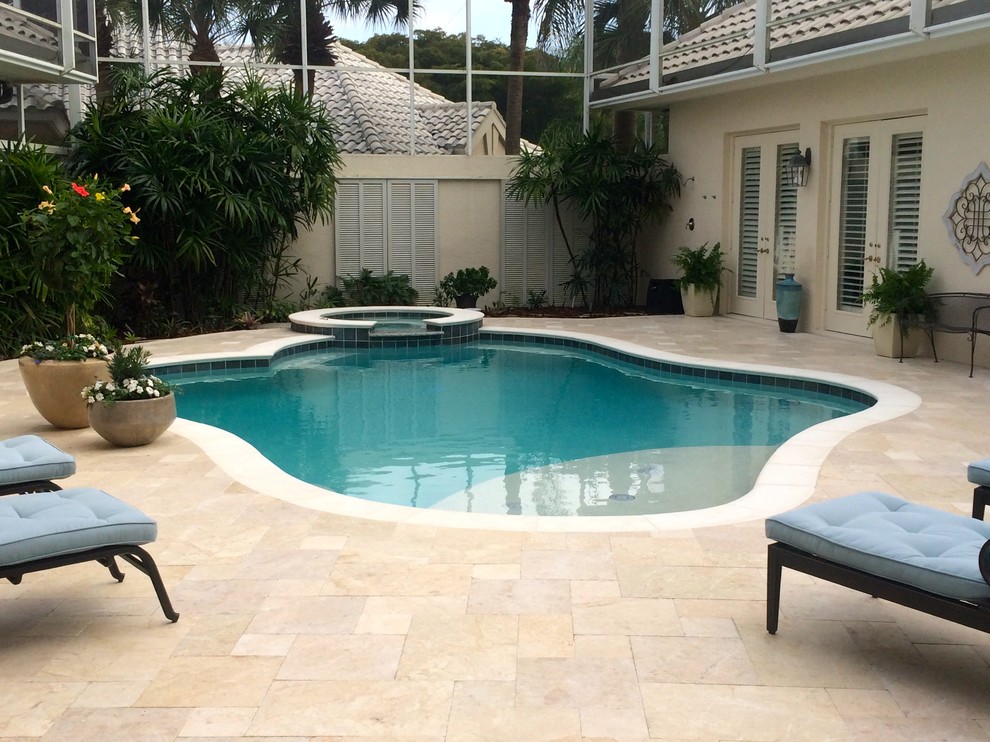 Design ideas for a mid-sized mediterranean courtyard custom-shaped pool in Miami with a hot tub and tile.