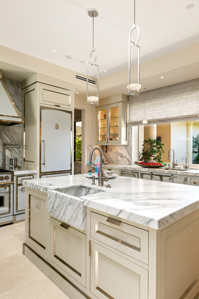Inredning av ett modernt mycket stort vit vitt kök, med en integrerad diskho, skåp i rostfritt stål, marmorbänkskiva, vitt stänkskydd, stänkskydd i marmor, vita vitvaror, flera köksöar och beiget golv