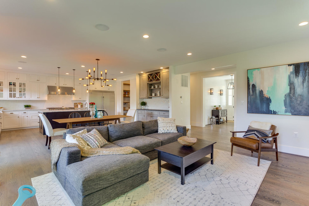 This is an example of a large arts and crafts open concept living room in DC Metro with white walls, medium hardwood floors, a standard fireplace, a wall-mounted tv and a tile fireplace surround.